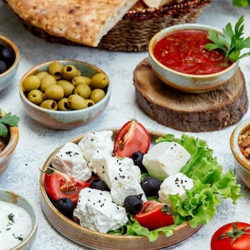 שולחן מזה קפריסאי בחוץ עם סלטים, זיתים ולחם טרי בפרוטארס
